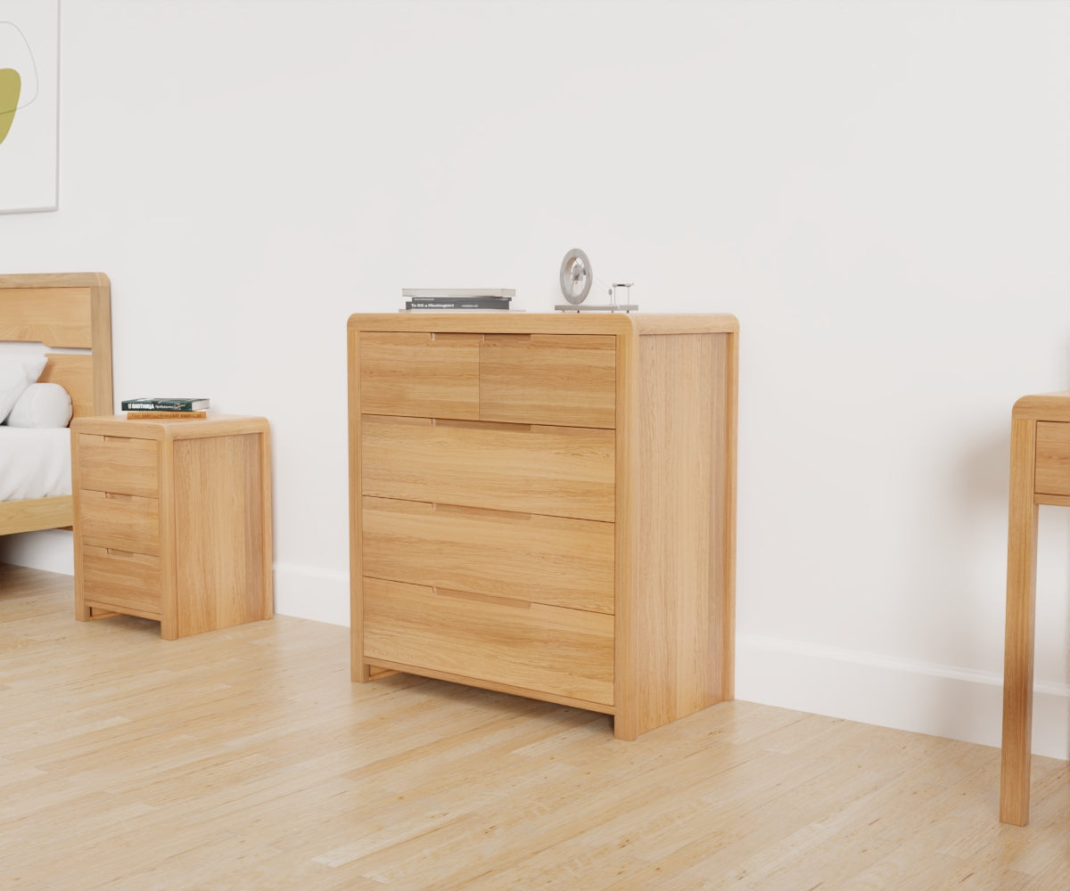 Julian Bowen Curve 3+2 Drawer Chest. Angled front view lifestyle image featuring other products from the range in the background.