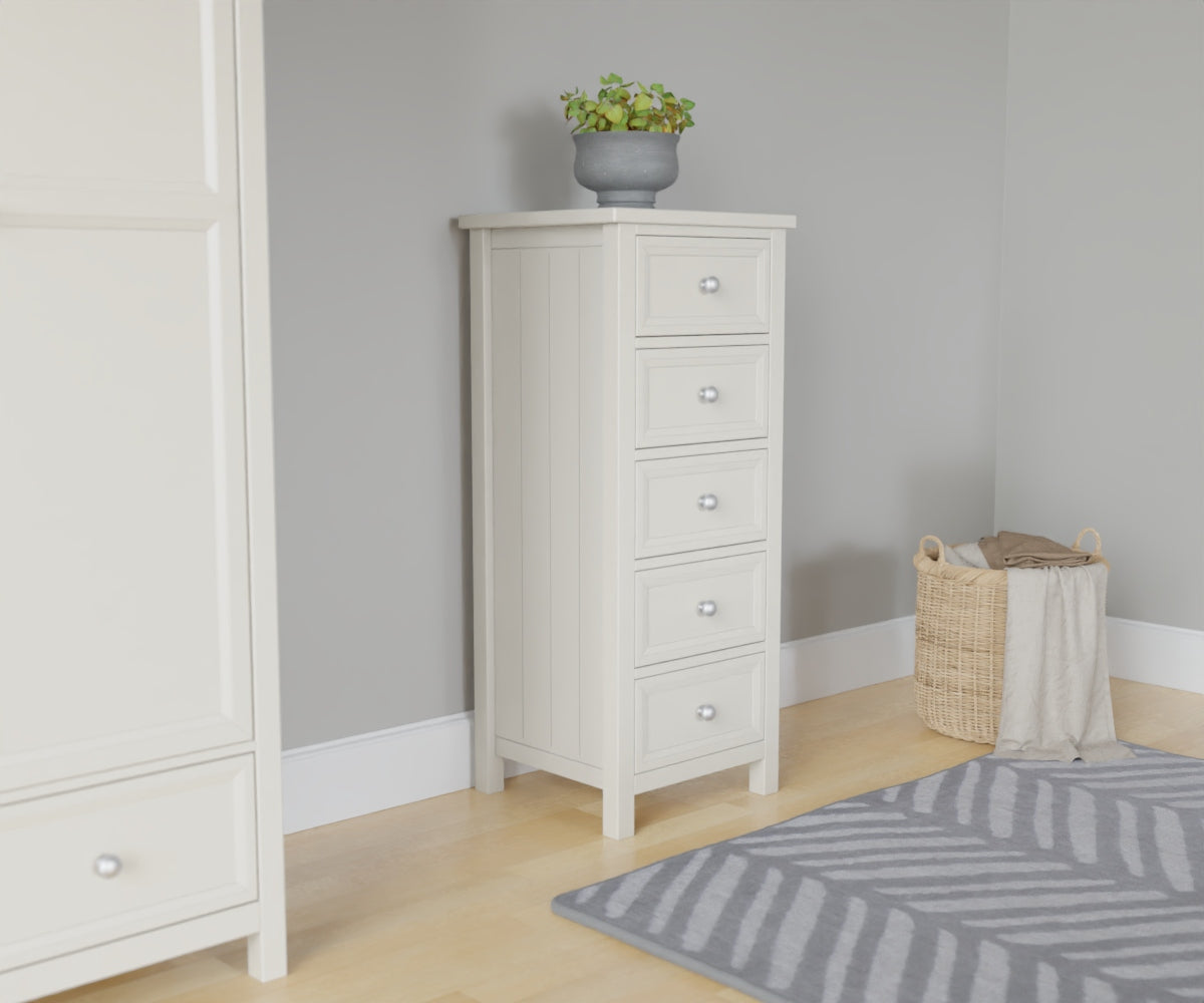 Maine 5 Drawer Chest in white has a square-edged top, with 5 equal vertical drawers with round handles. This lifestyle image features other products from the Julian Bowen Maine range.